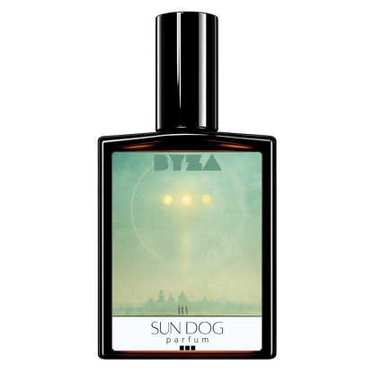 A rectangular perfume bottle with a glossy black cap and a front label reading 'BYZA' and 'SUN DOG parfum'. The label artwork shows a pale teal sky with a bright sun and a silhouetted city skyline.